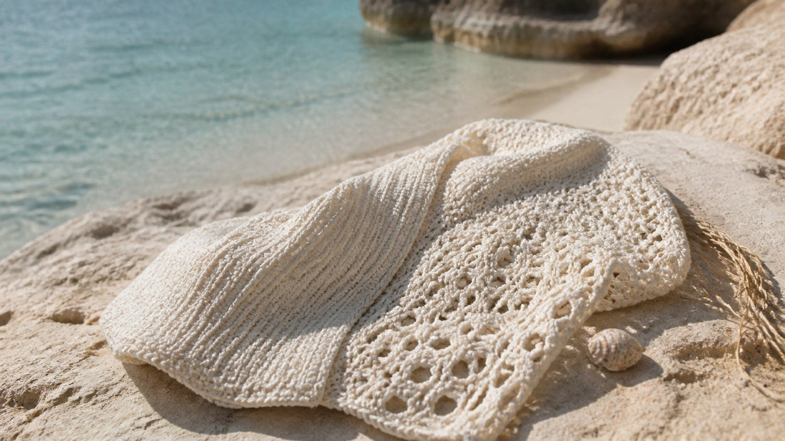 Ivory crochet textiles with dense and open handwork arranged on sunlit limestone beside clear turquoise water